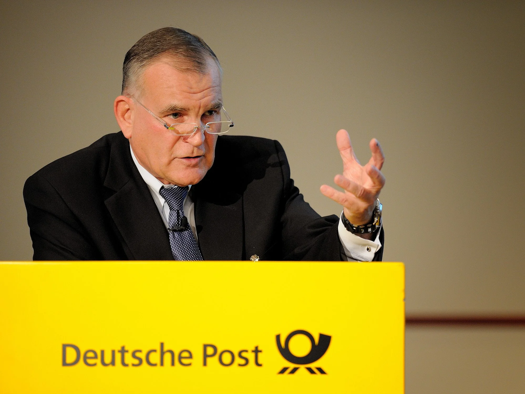 Redner am Pult mit Deutsche-Post-Logo während einer Unternehmenstagung in Bonn – Tagungsfotografie für Kongresse und Konferenzen.