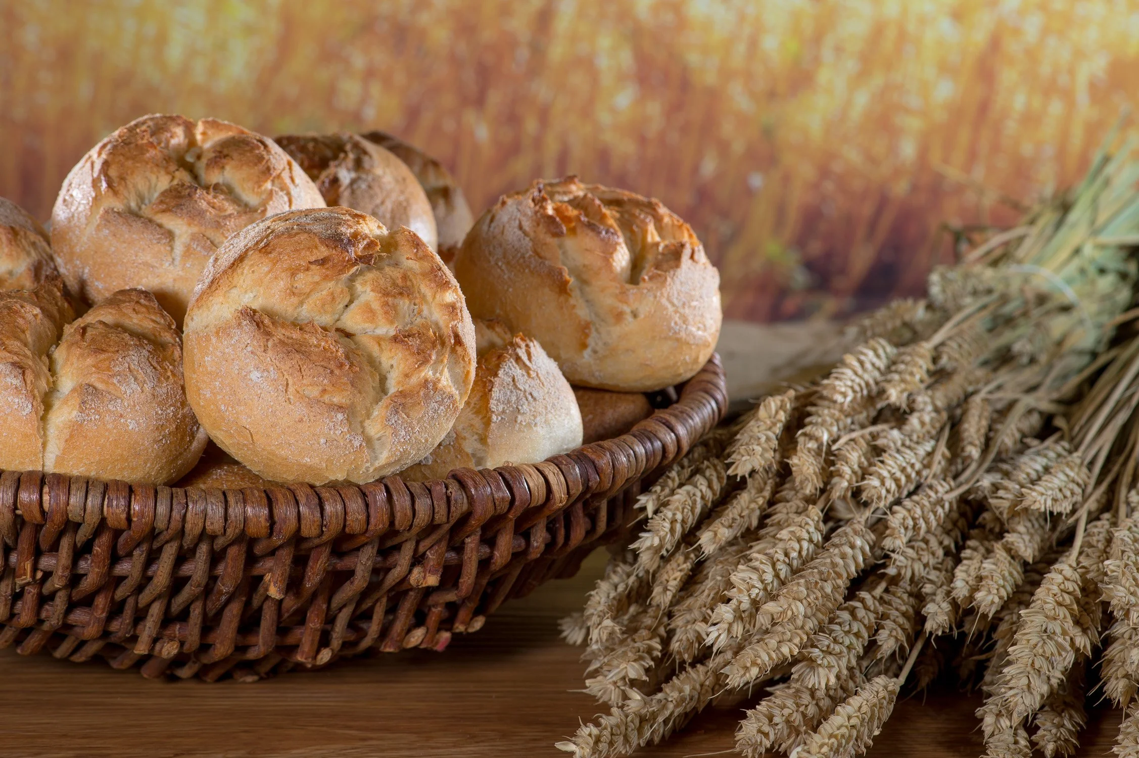 Frische, knusprige Brötchen in einem Weidenkorb auf Getreideähren – Food-Produktfotografie für eine Bäckerei