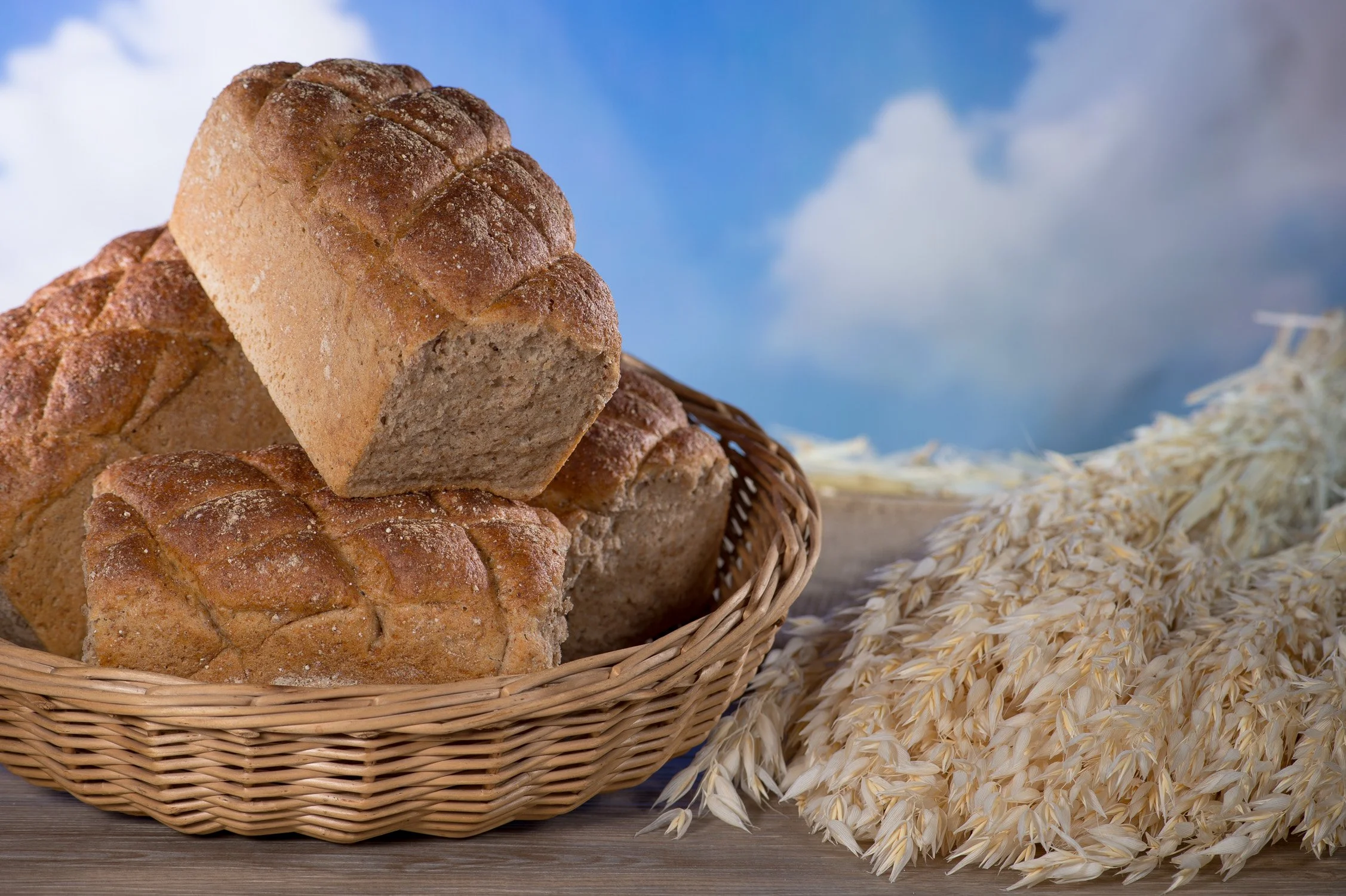 Rustikale Landbrote in einem Korb vor blauem Himmel – Food-Produktfotografie für Backwaren