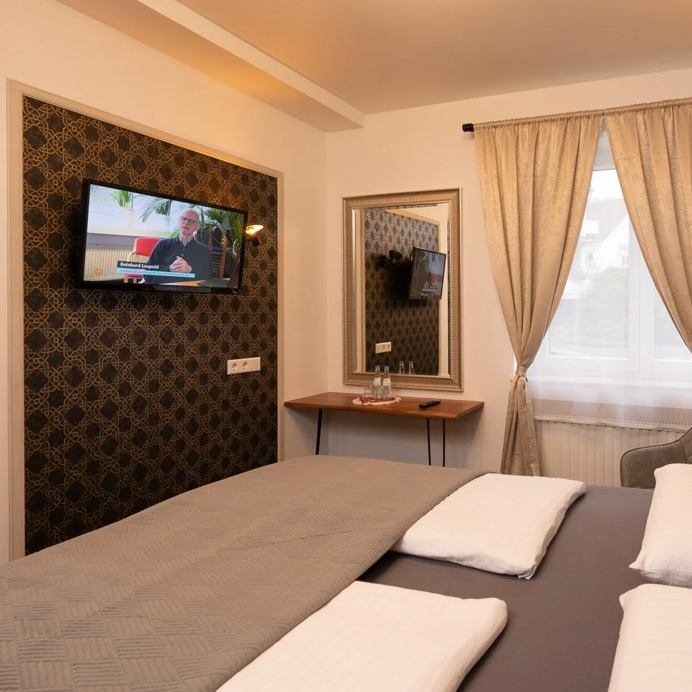 Doppelzimmer mit Bett, Fernseher und Spiegel – Hotelfotografie in Köln.
