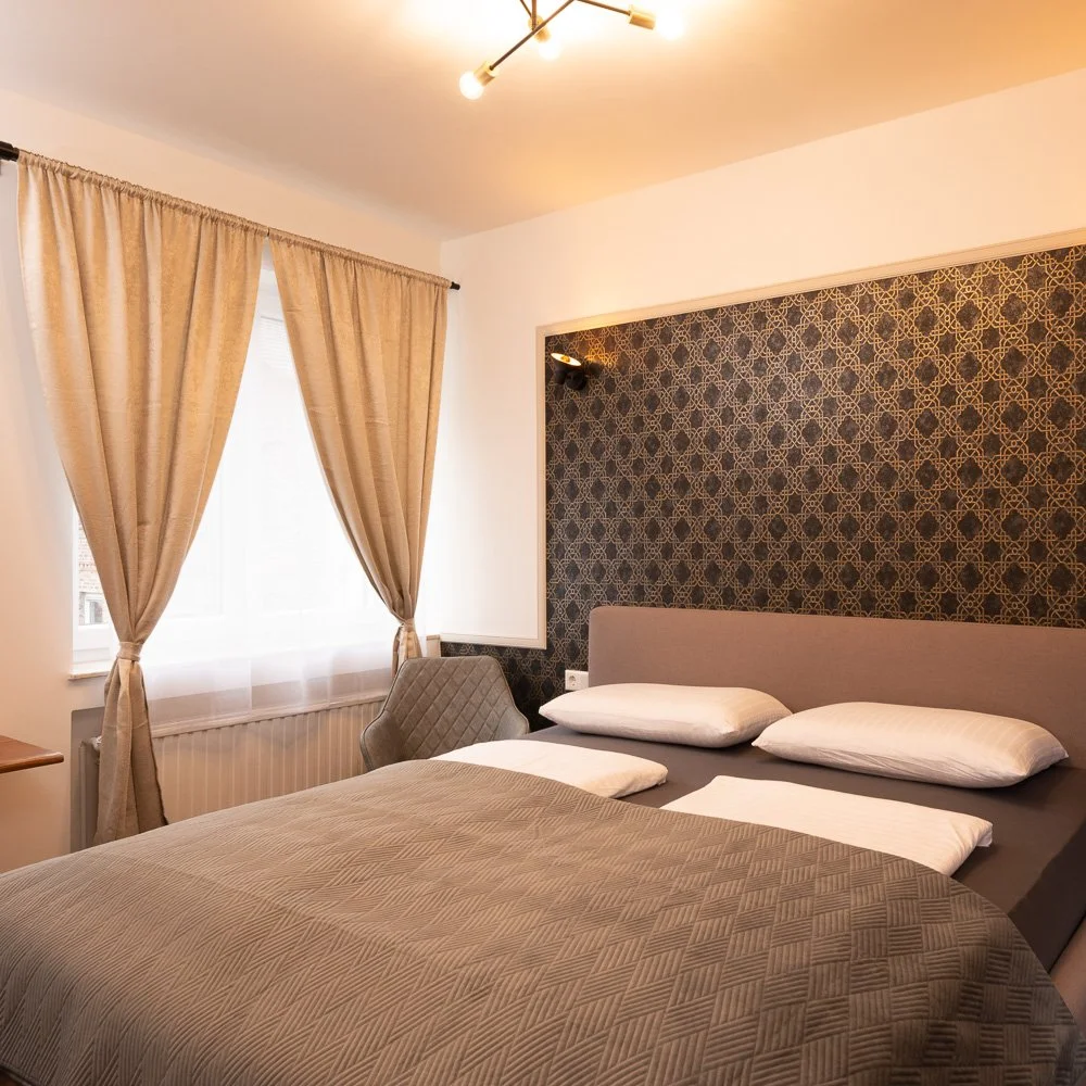 Doppelzimmer mit Bett und Fenster mit Vorhängen – Hotelfotografie in Bonn.