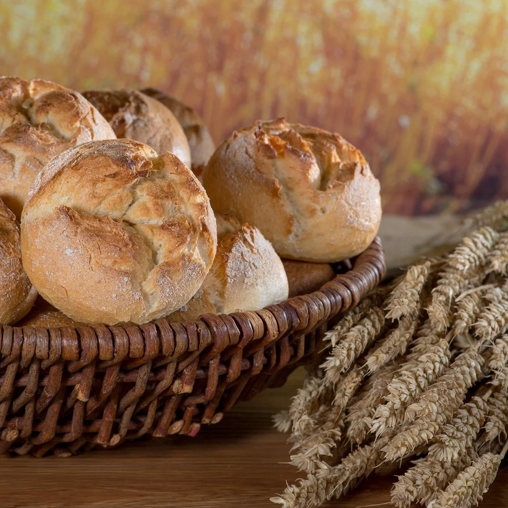 Frische, knusprige Brötchen in einem Weidenkorb auf Getreideähren – Food-Produktfotografie für eine Bäckerei