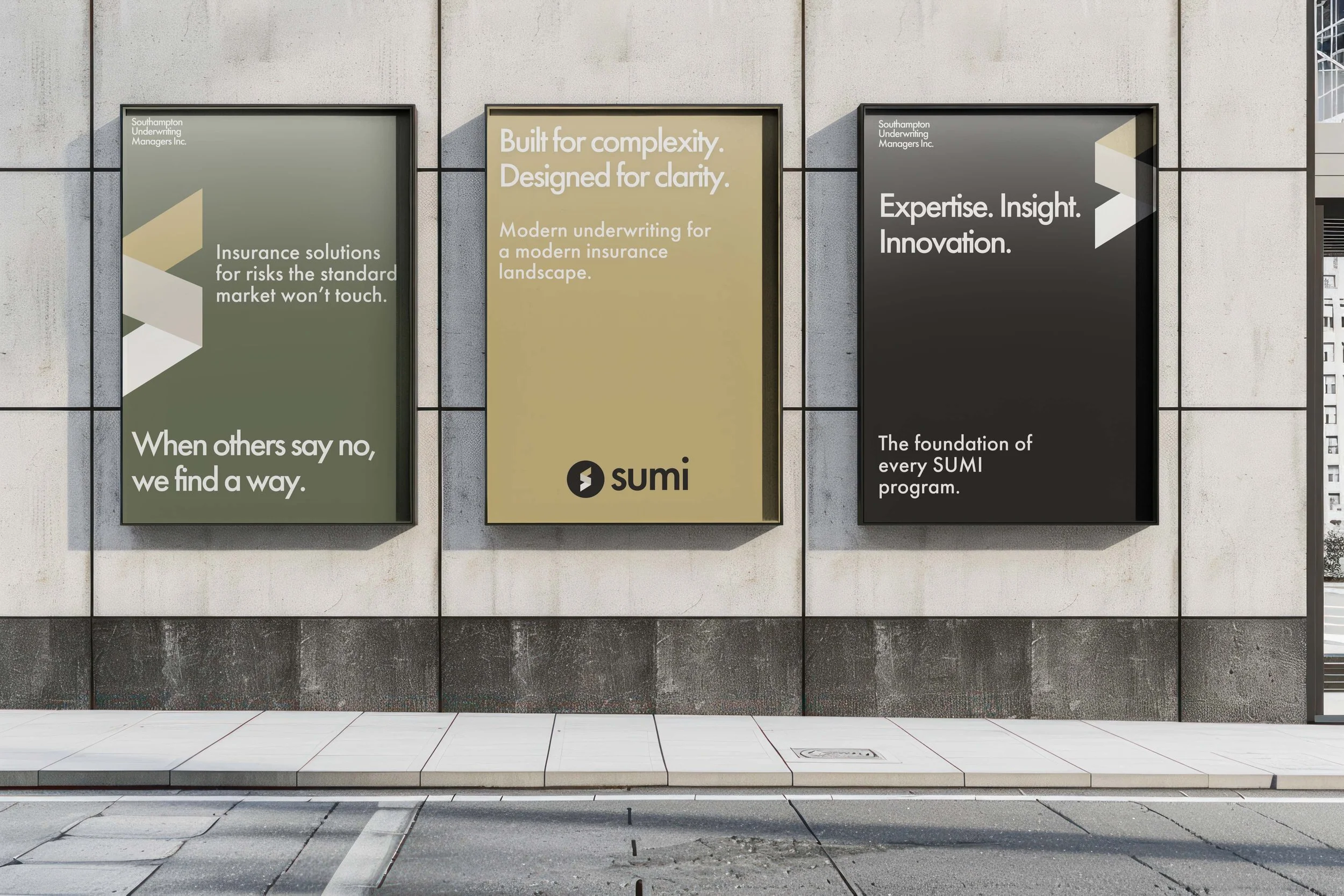 Three large advertising posters on a concrete wall outside a building. The first poster on the left promotes insurance solutions for risks the market won't encounter. The middle poster emphasizes modern underwriting founded for clarity, and the third poster on the right highlights expertise, insight, and innovation. The posters are framed in black and have a minimalist, professional design.