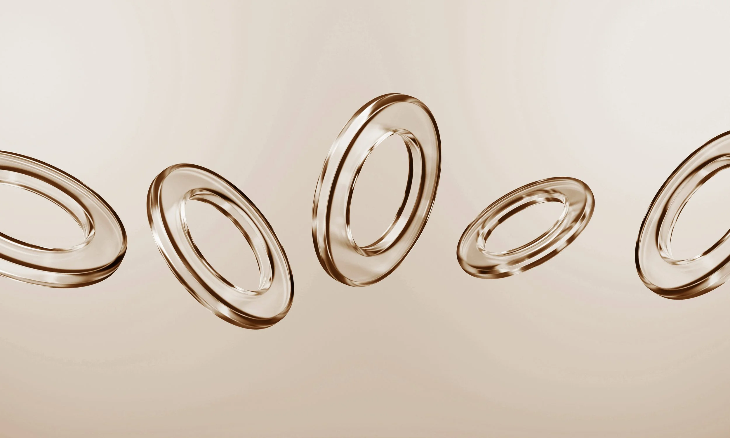 Multiple metallic rings floating against a neutral background, showing reflections and shadows.