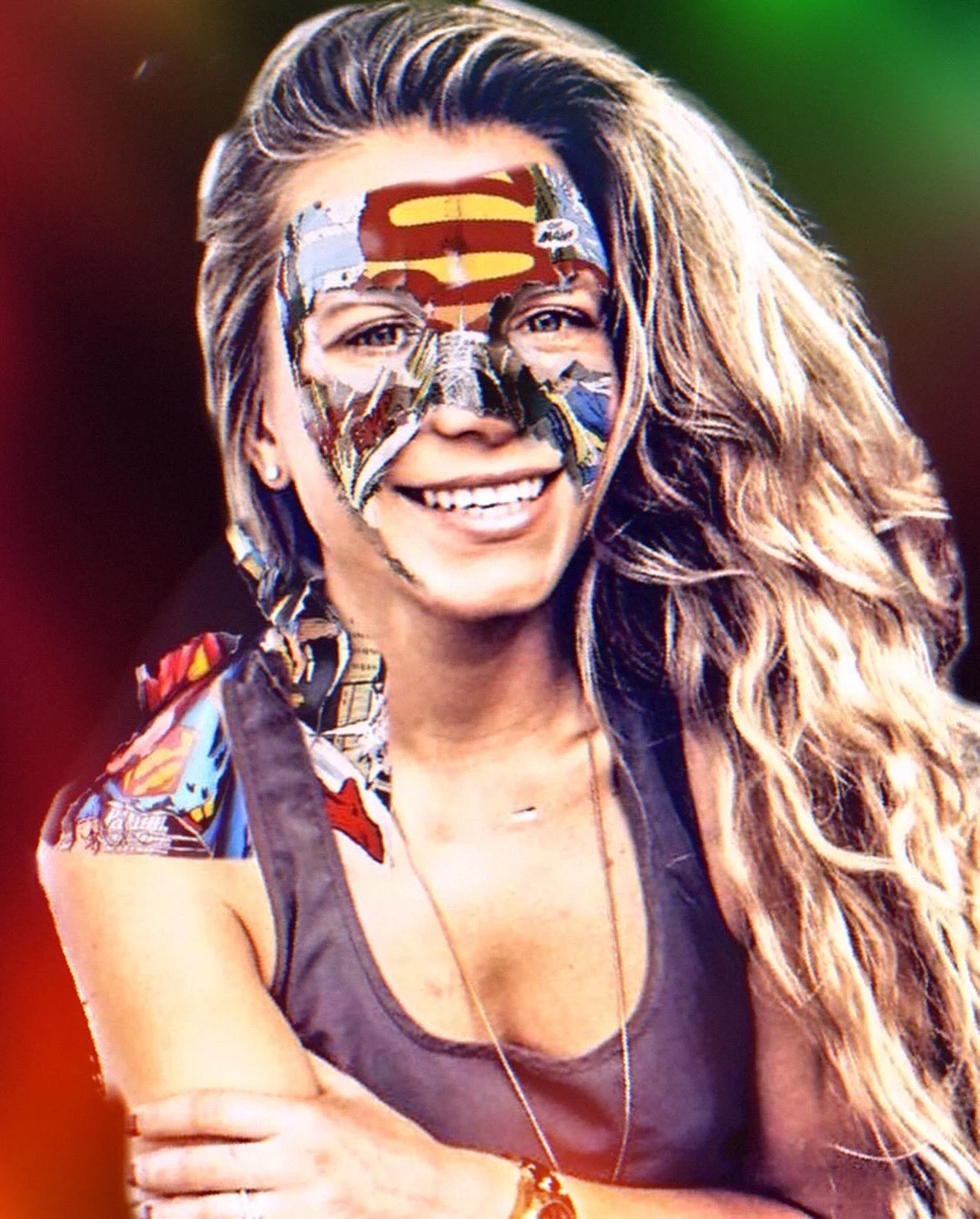 A woman with wavy blonde hair smiling, with a Superman logo face paint mask on her face.