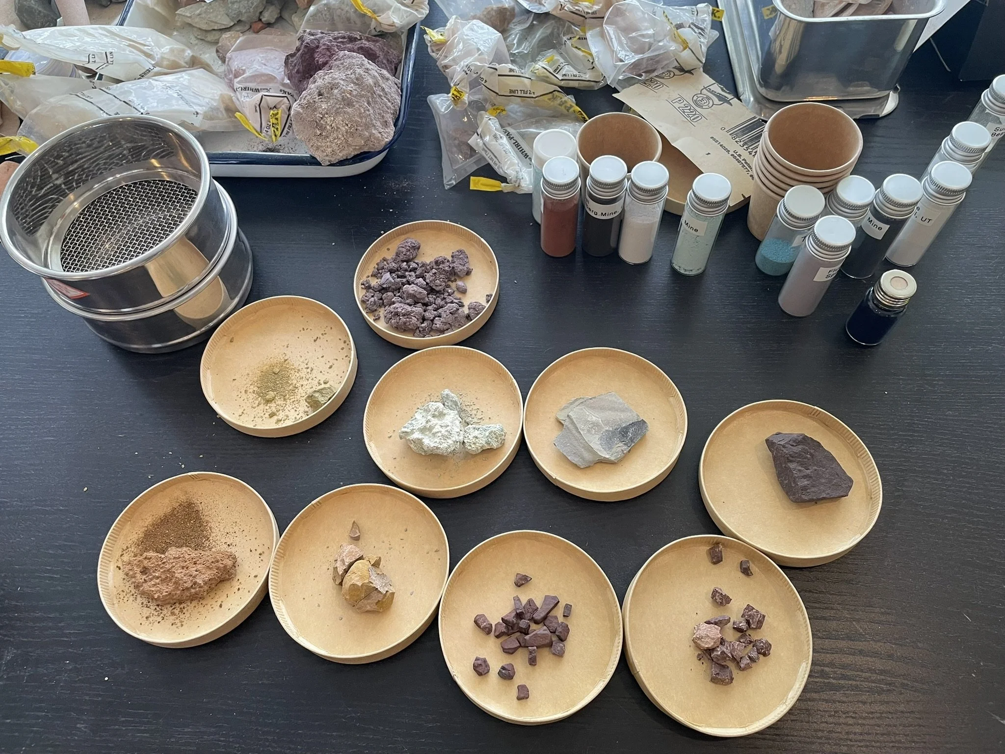 A collection of colorful rocks laid out on a table for the pigment workshop
