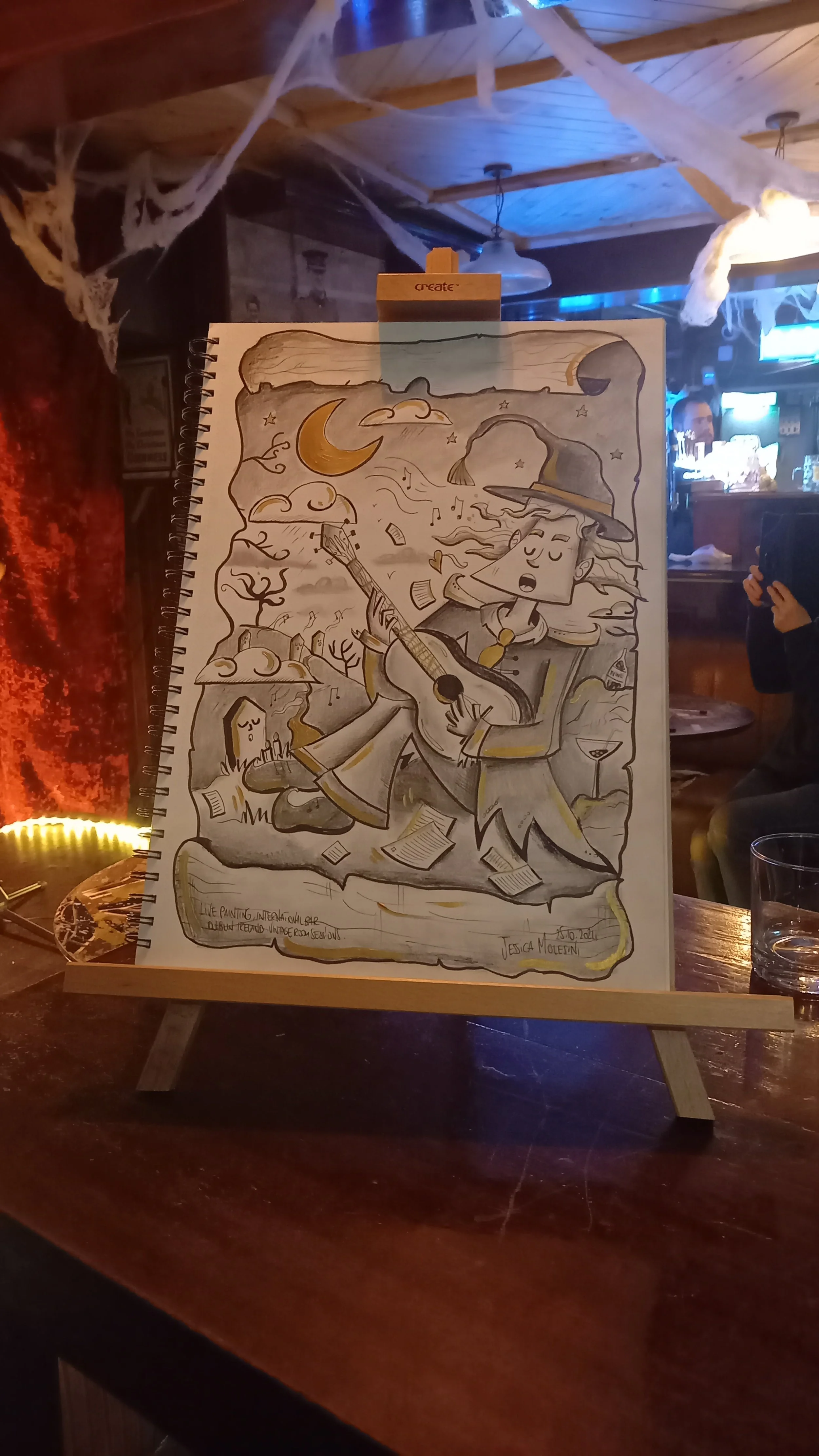 A sketch of a witch playing guitar among floating papers and trees, with a crescent moon and clouds in the background.