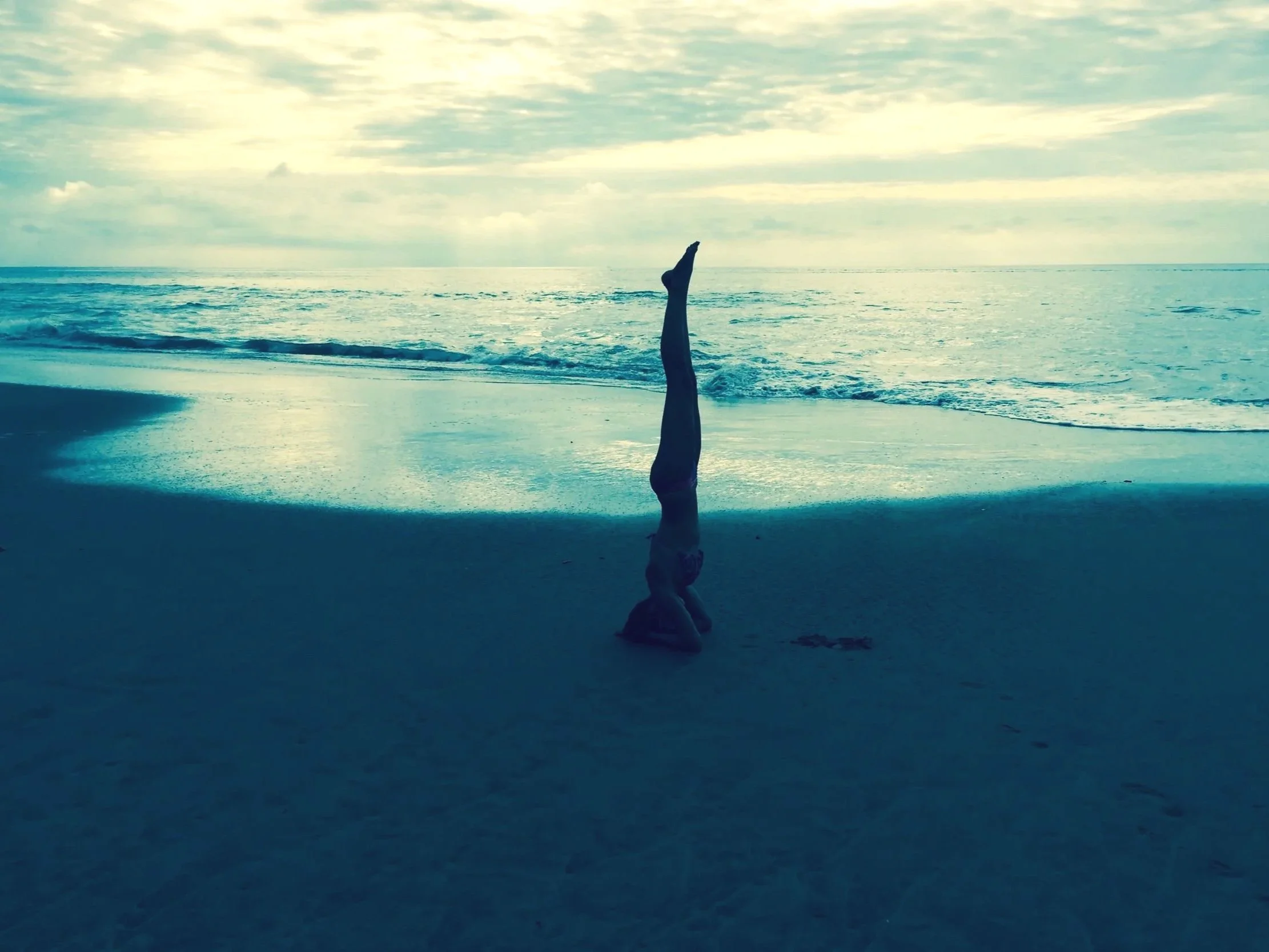 A silhouette of a person performing a headstand on a beach near the ocean waves, under the word Relaxation.