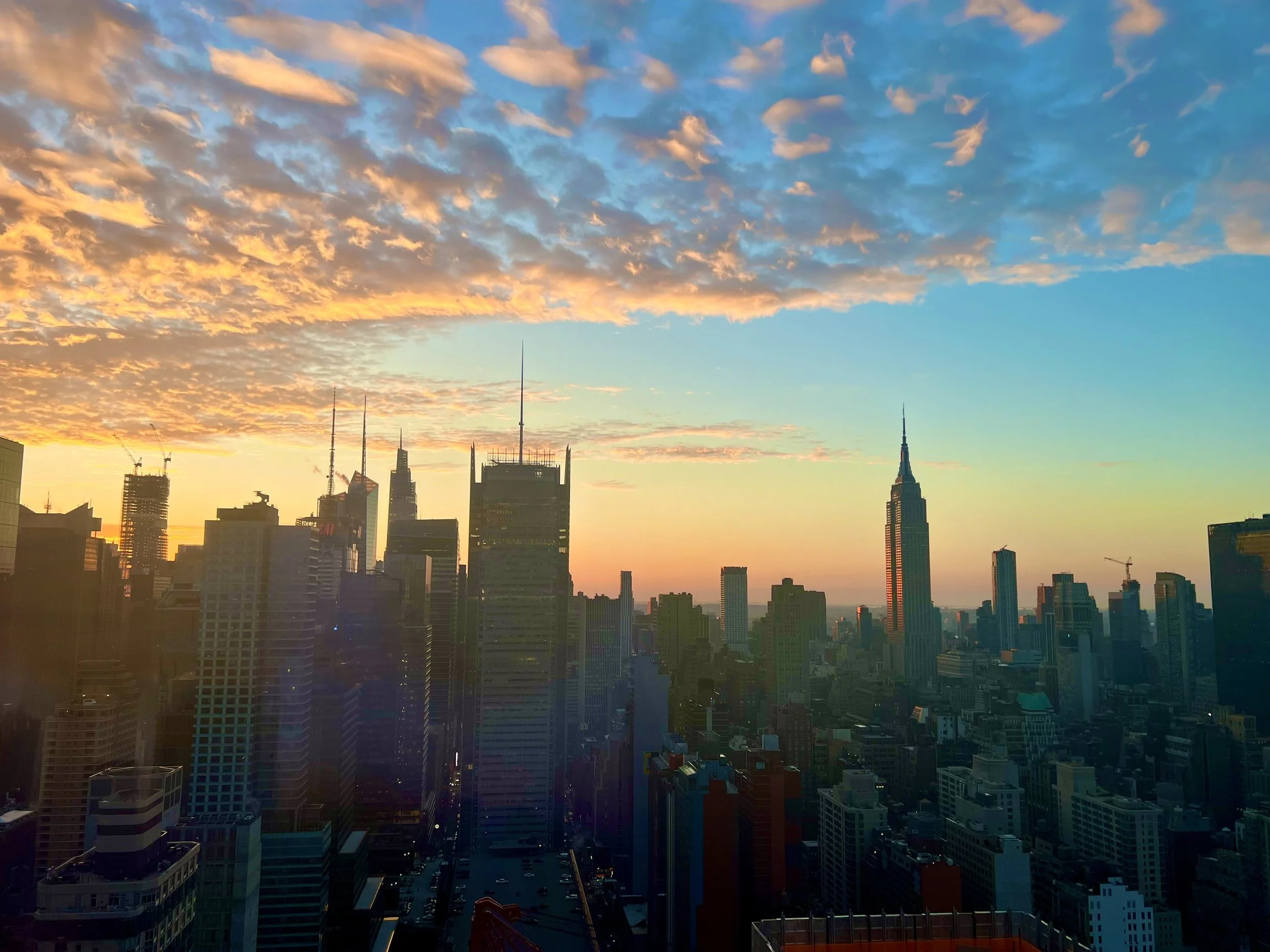 A colorful sunset over the New York City skyline featuring the Empire State Building, illustrating the NYC curated culinary guide.