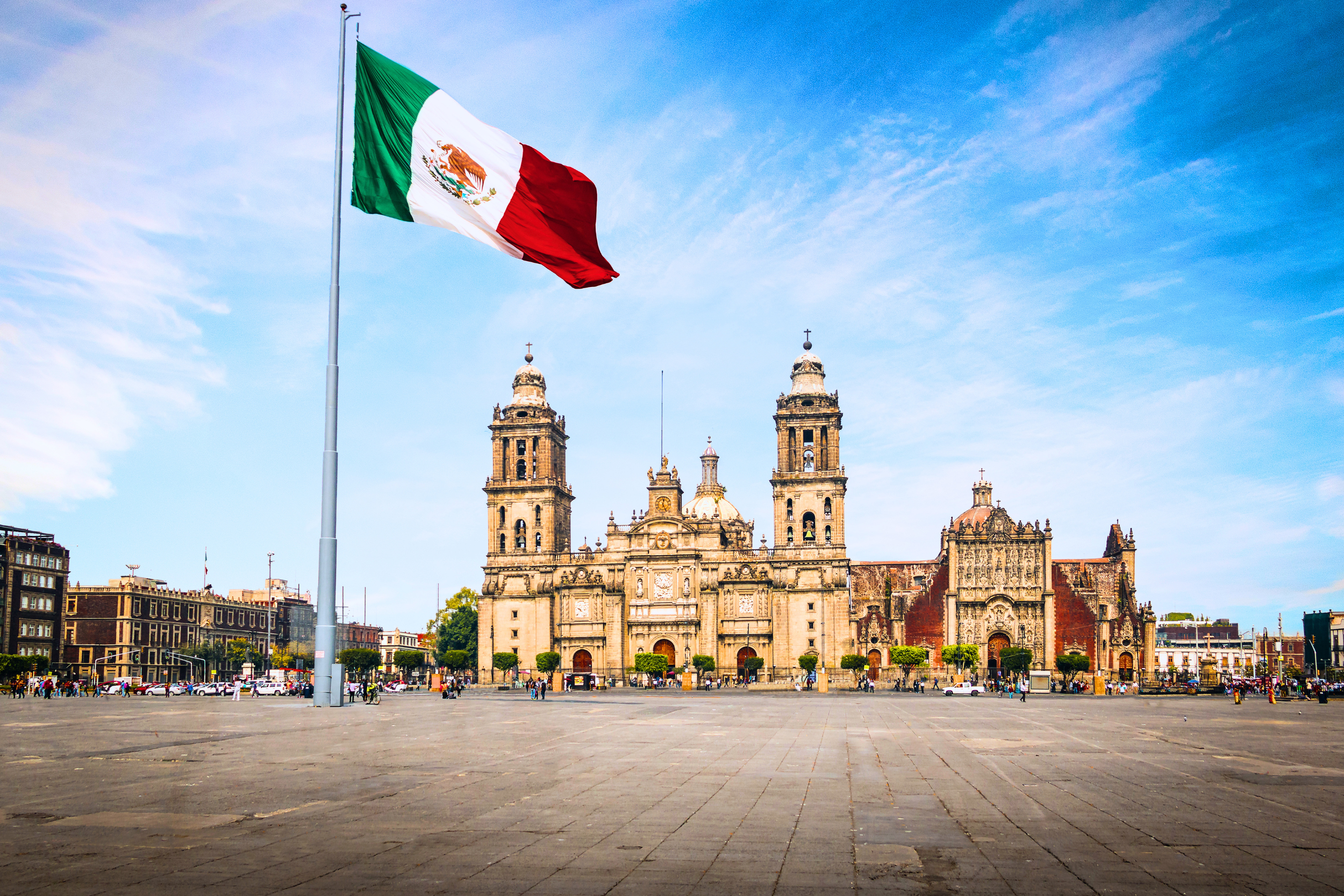 The historic Metropolitan Cathedral and Zócalo plaza flying the Mexican flag, representing the Mexico City culinary and restaurant guide.