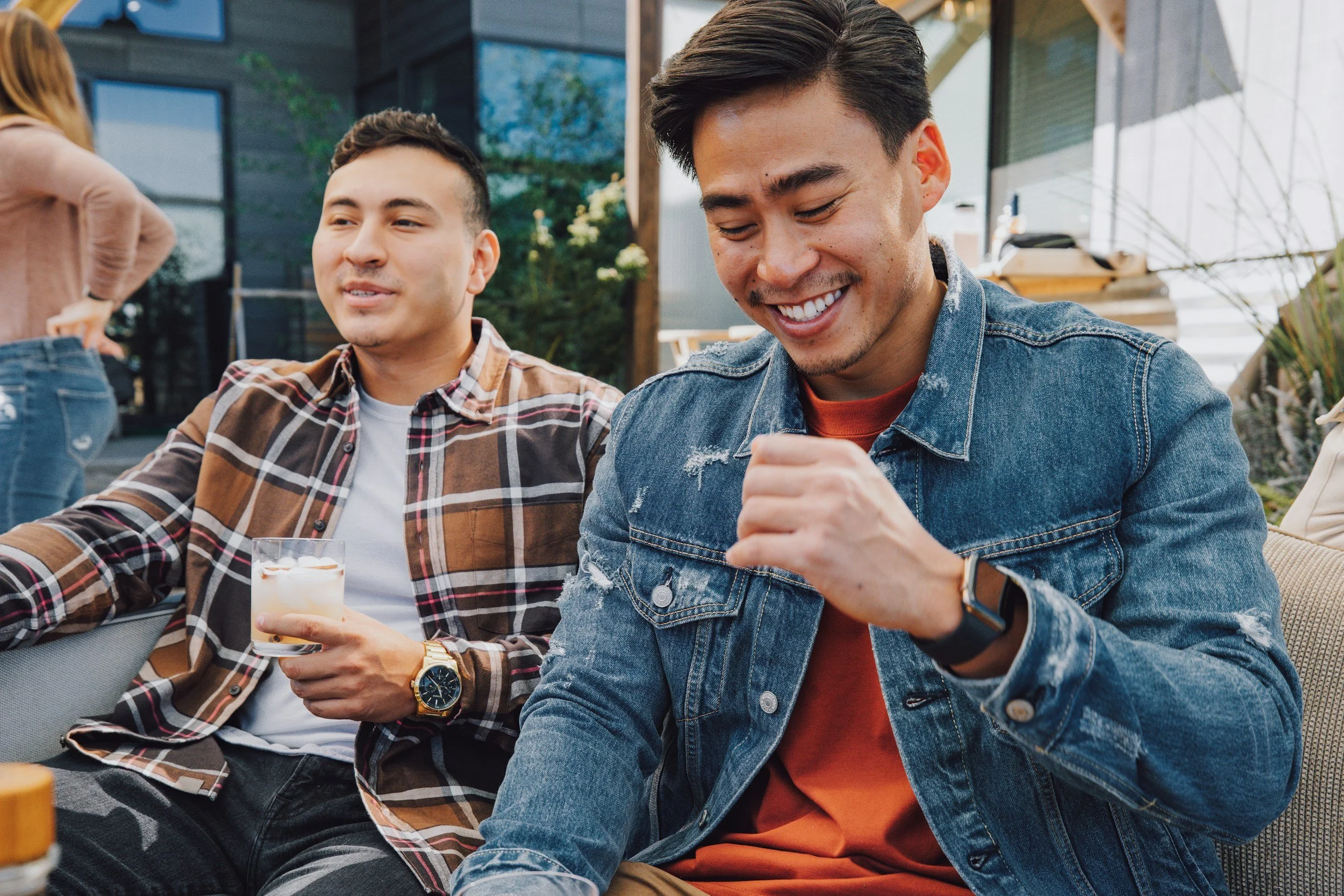 Two men sit smiling discussing the success they have had in therapy.