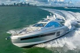 A luxury yacht sailing at high speed on the water with a city skyline in the background.