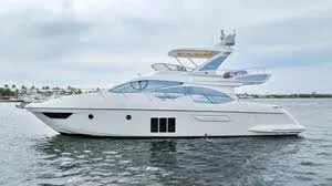A large white yacht with multiple decks sailing on calm water under a cloudy sky.