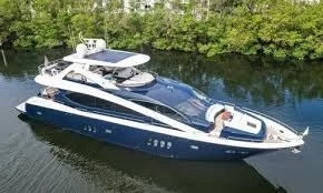 A Sunreef Manhattan 86 yacht docked on a calm river with green trees in the background.