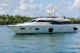 Luxury white yacht sailing on calm water near a green shoreline under a partly cloudy sky.