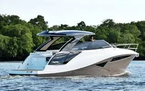 Luxury white and gray yacht cruising on water with green trees in background