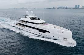 A 50 meter Heesen  large luxury yacht sailing on the water with a city skyline in the background.