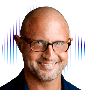 Mountain range with snow-capped peaks and a cloudy sky and some grassland in the foreground.
