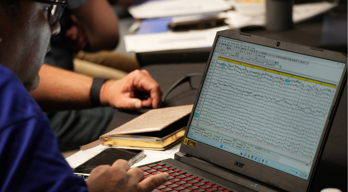 Person analyzing brain wave patterns on a laptop at a conference or study session.