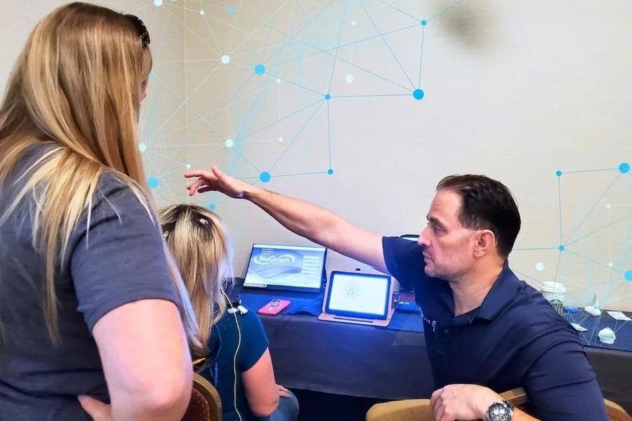 Modern houses on a hillside with snow-capped mountains in the background under an overcast sky.