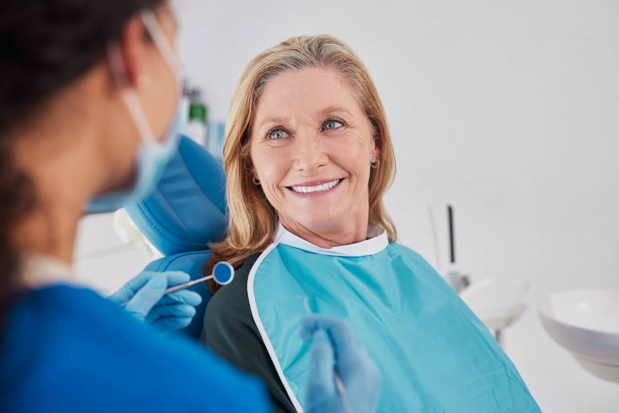 Mature woman sits in oral surgeon chair smiling