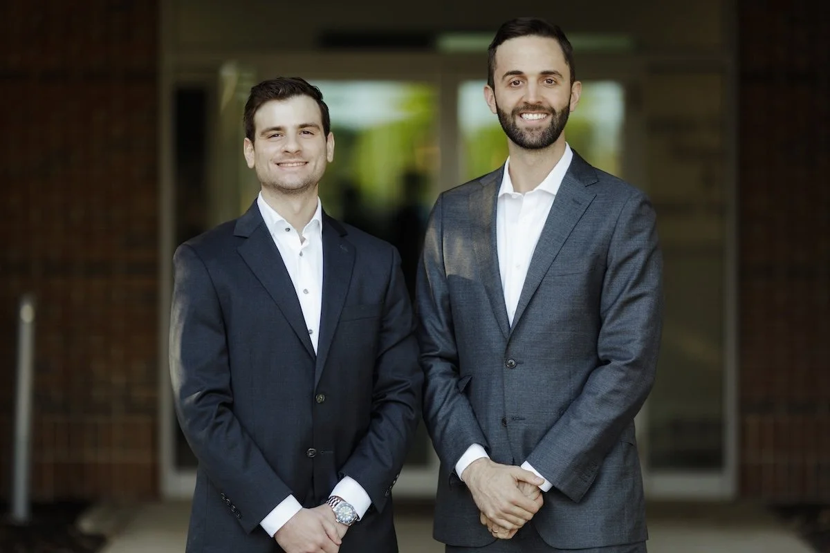 Dr. Feigenbaum and Dr. Bulcher pose in front of the Center for Oral Surgery + Dental Implants