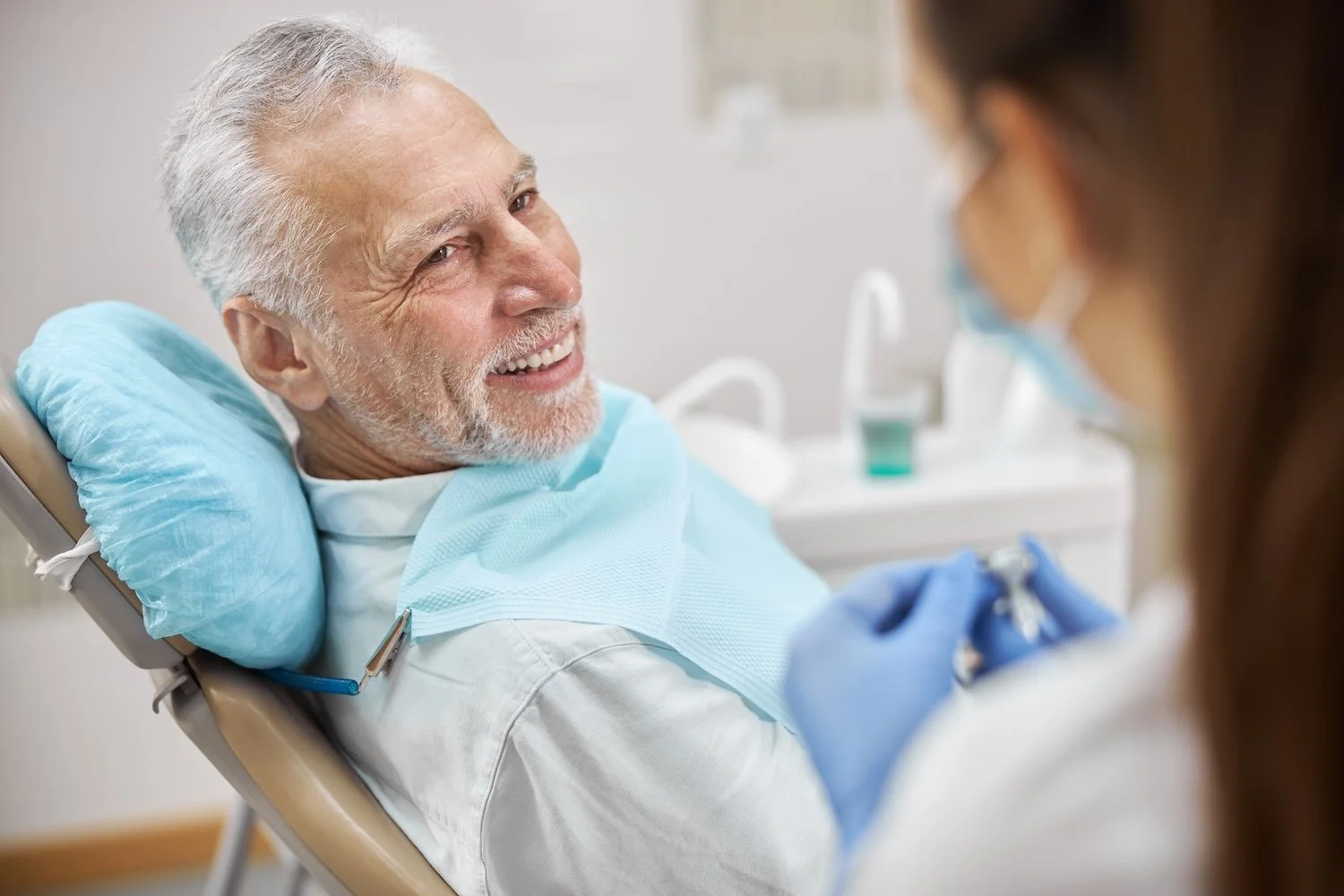 Older male dental implant patient smiling at doctor