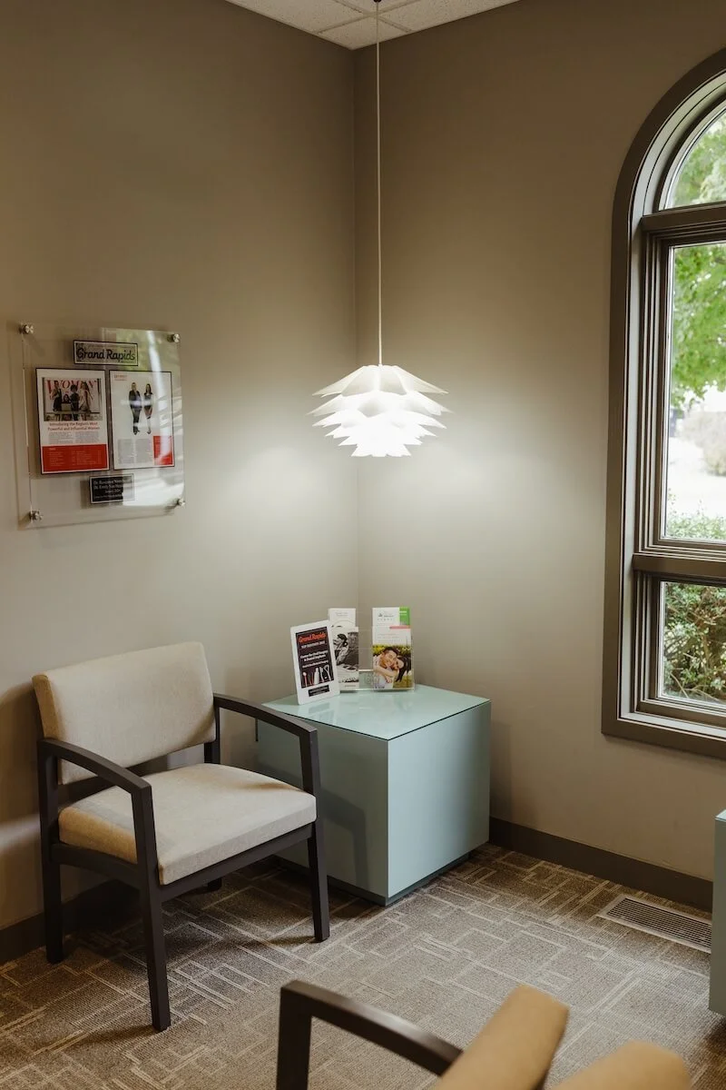 Center for Oral Surgery + Dental Implants waiting room corner with chair and reading materials