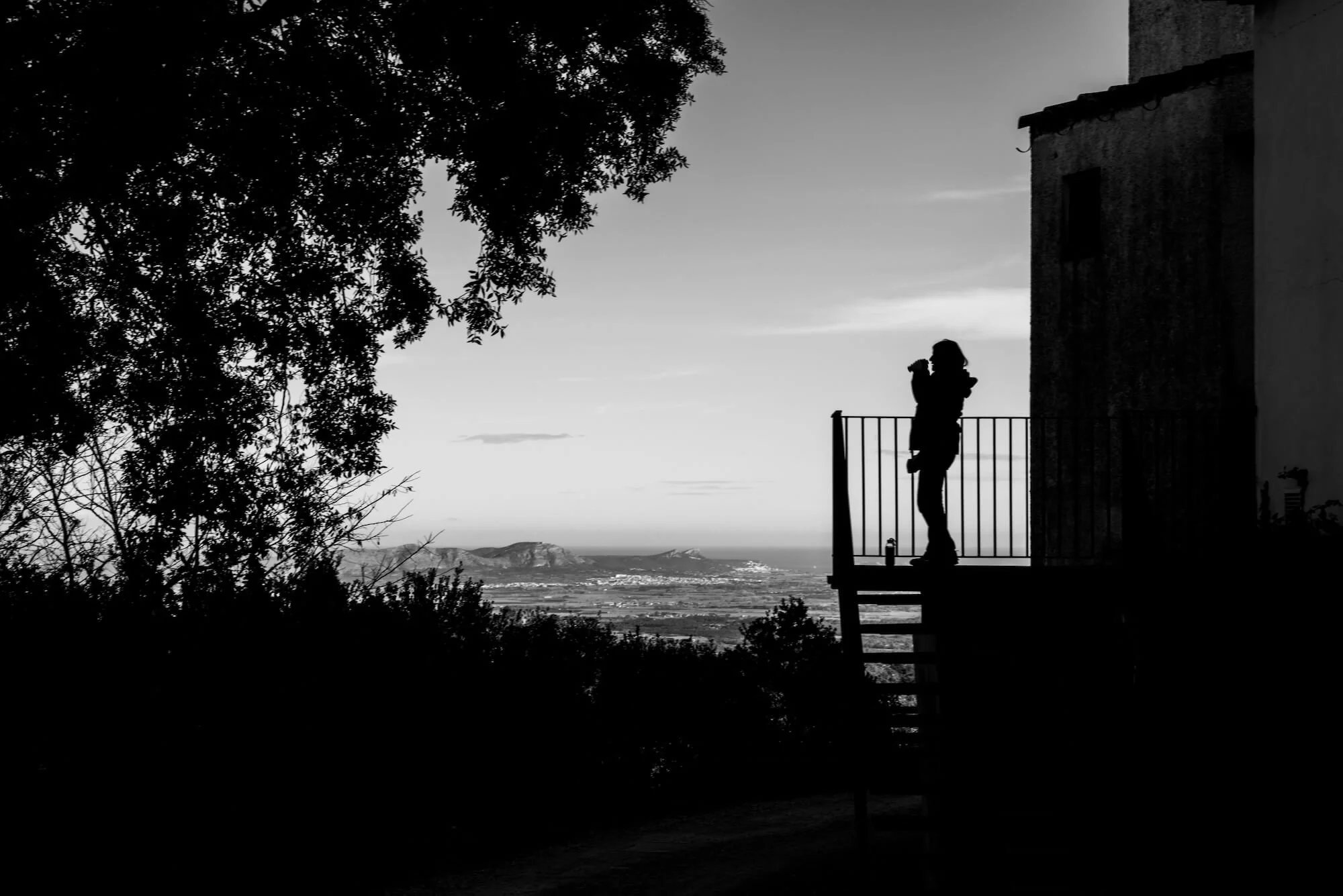 Black and white silhouette of a person standing on a balcony overlooking a vast landscape — evoking the clarity, perspective, and emotional space found through compassionate individual therapy