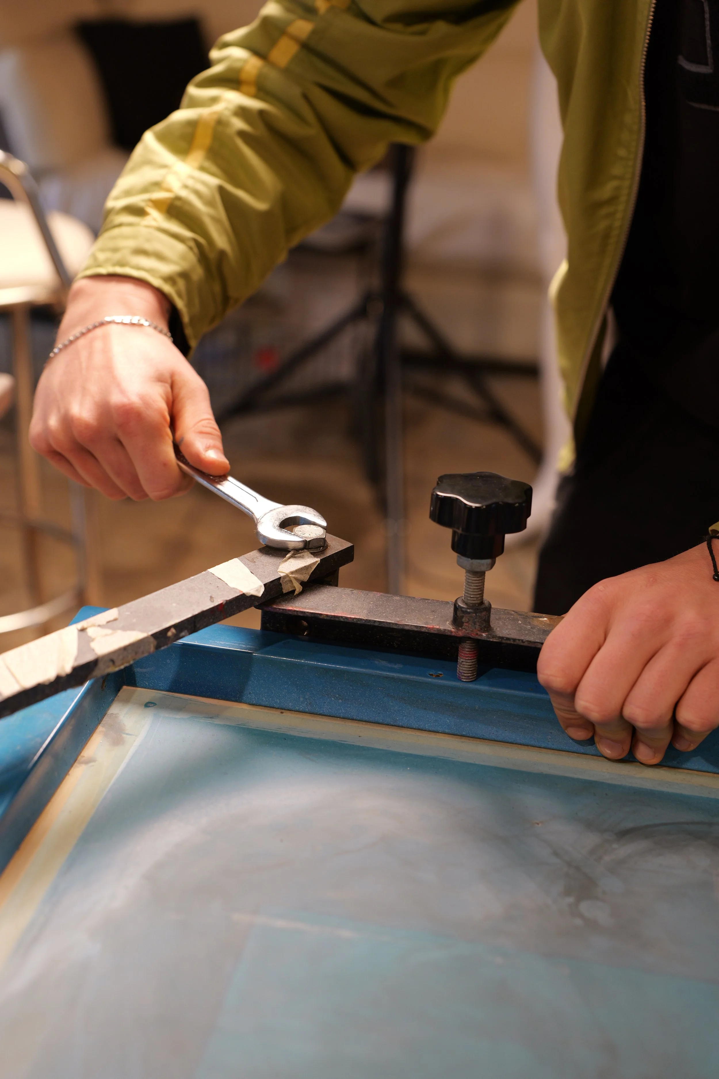 Persona che utilizza una chiave inglese per fissare un braccio di una giostra serigrafica.