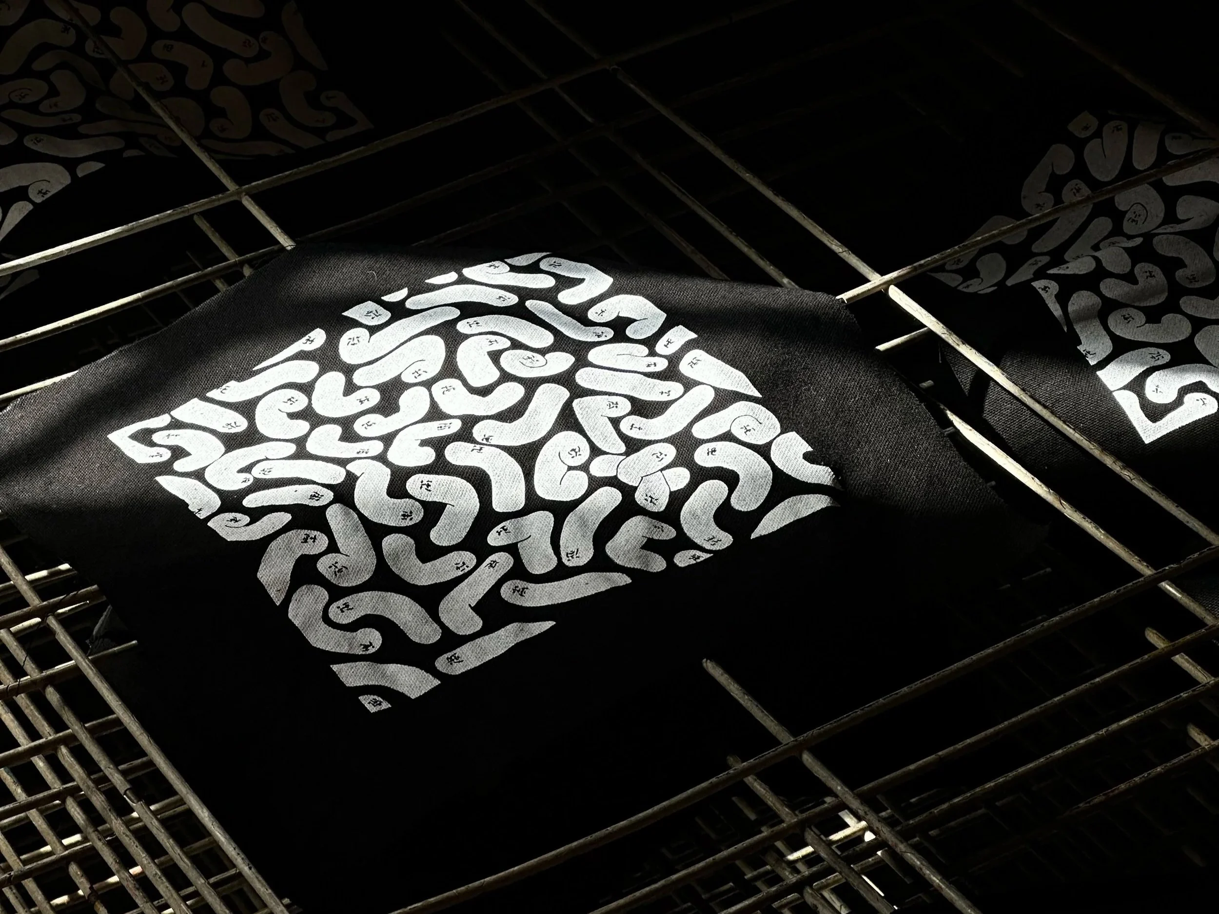 Black fabric with white comic-like texture on top of a metal grill.