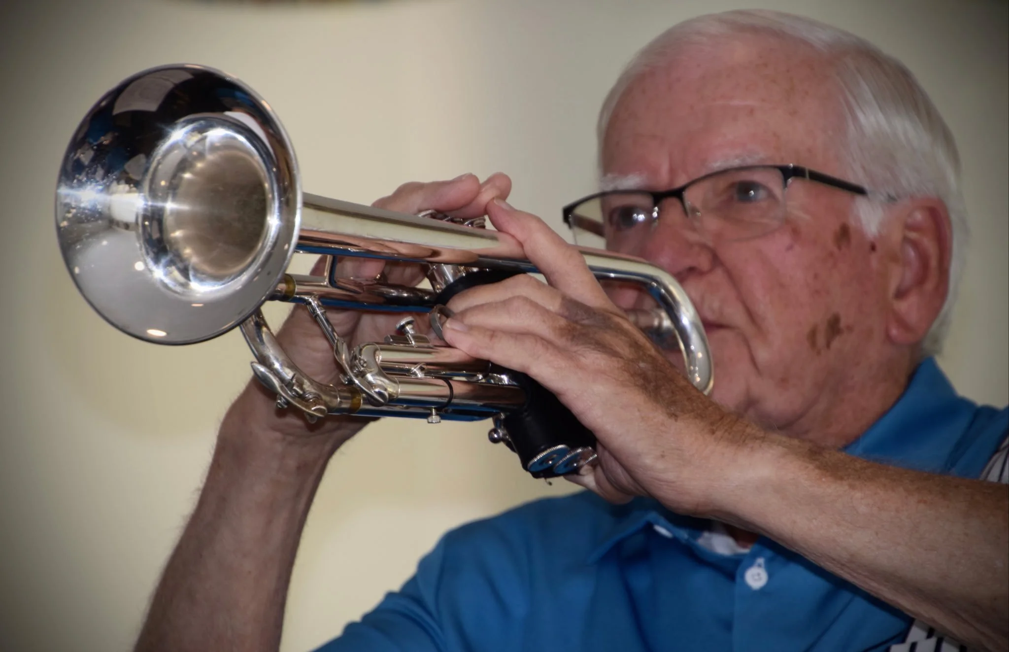 Close-up of a smiling older man with glasses and short gray hair, wearing a green shirt.