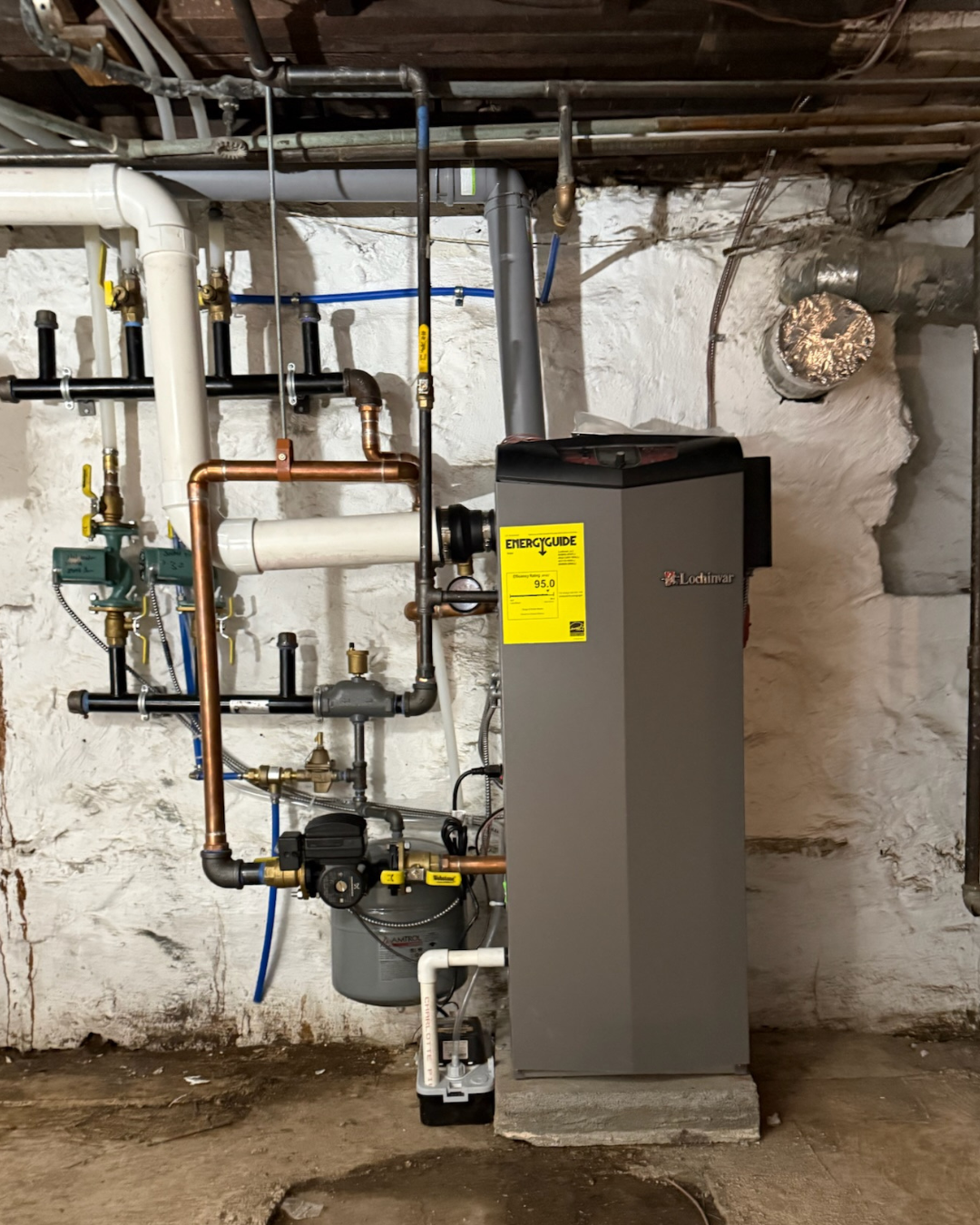 A basement utility room with a boiler system and various pipes and valves.