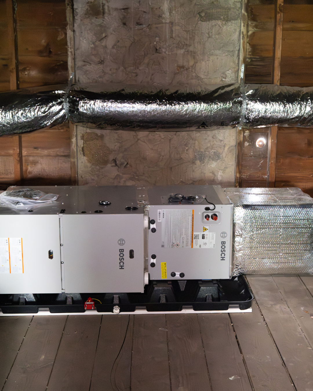 Bosch HVAC unit installed in an attic space with wooden ceiling and ductwork.