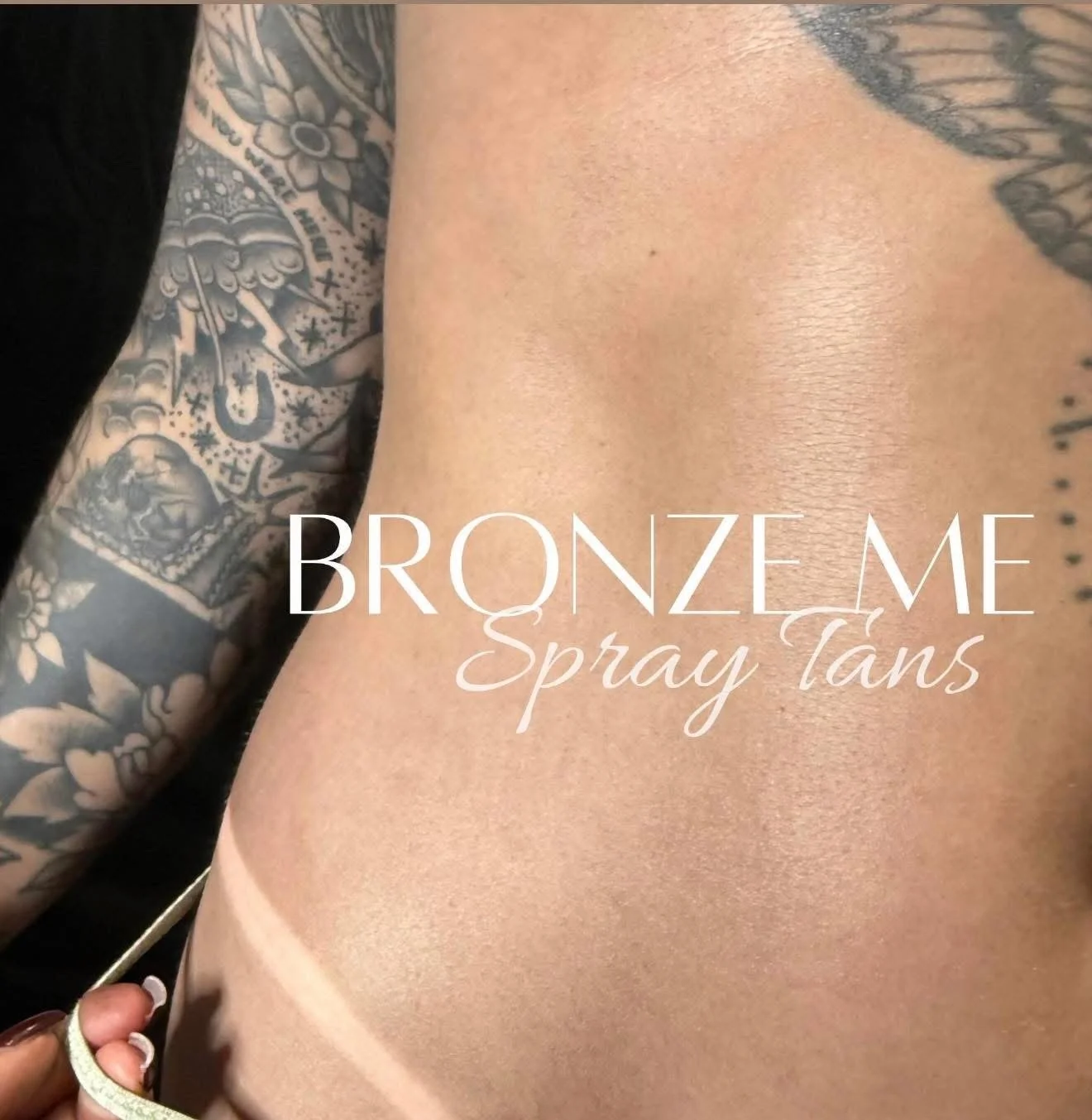 Close-up of a tattooed arm and shoulder with a bronzed, glowing skin tone, advertising a spray tan service.