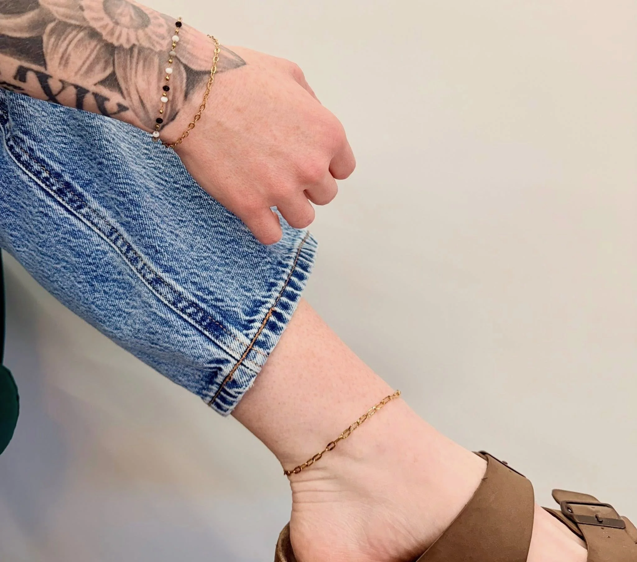Several gold and silver chain necklaces displayed on a white jewelry stand, with one featuring colored beads.