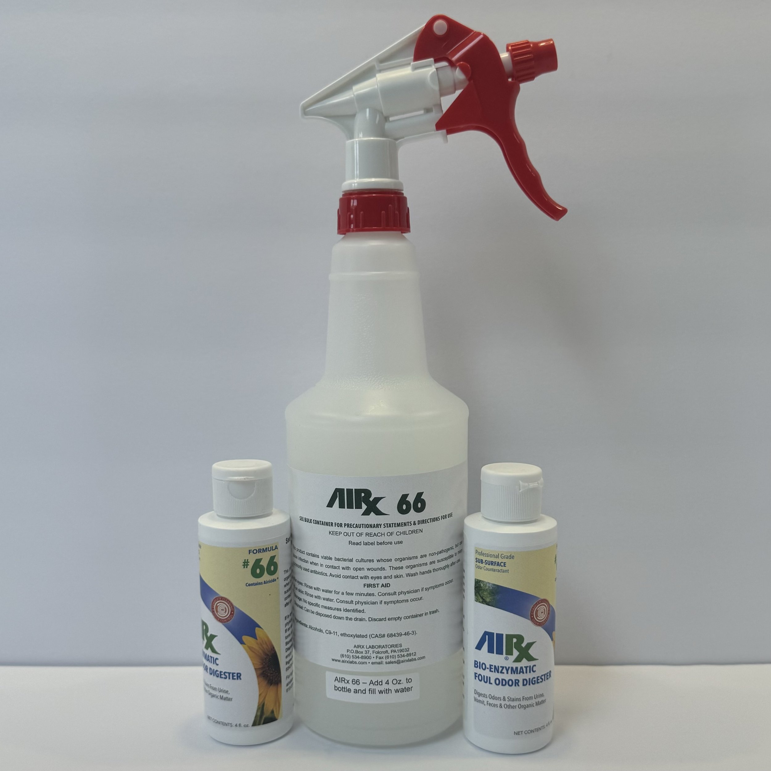 A spray bottle labeled 'AIRX 66' surrounded by two smaller bottles, one labeled 'BIO-ENZYMATIC FOUL ODOR DIGESTER' and the other with a sunflower image, all on a white surface against a plain light gray background.