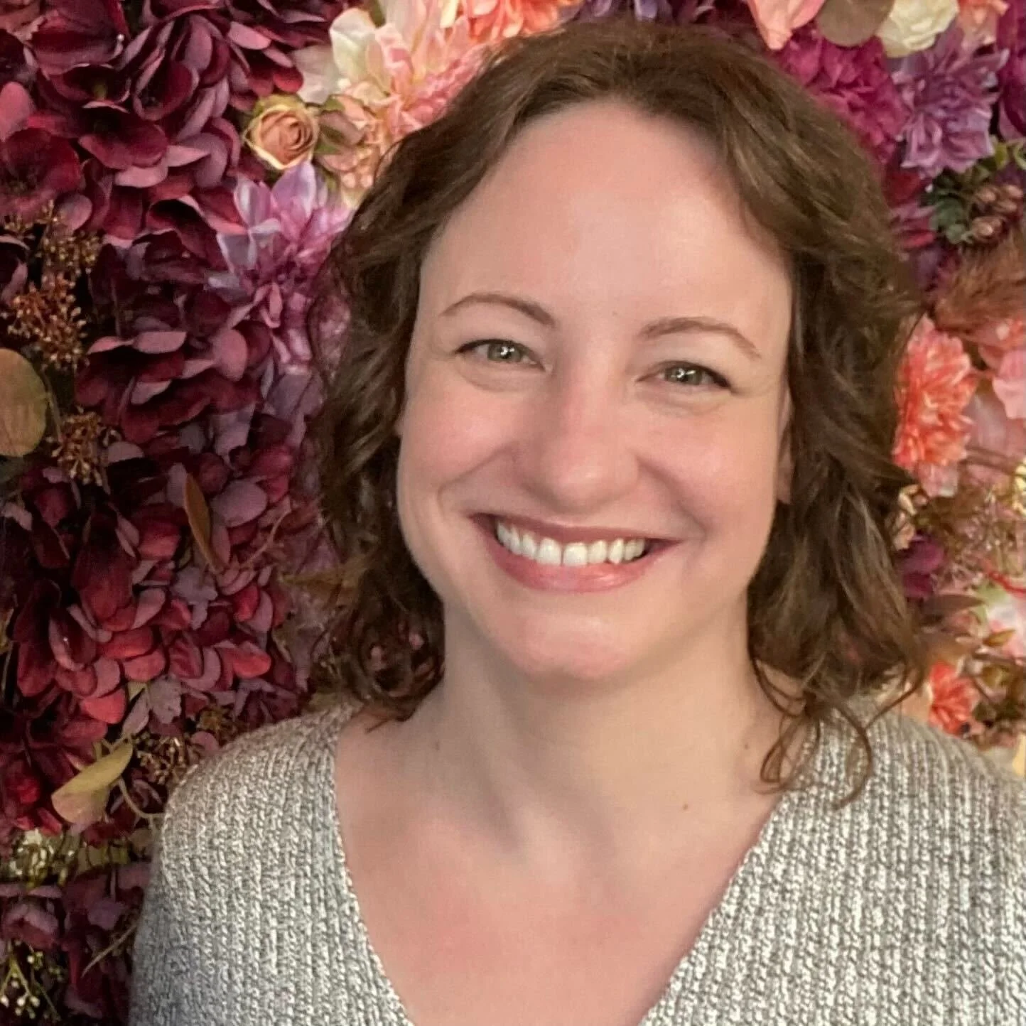 A headshot of Cassie Ericsson in front of a flower background