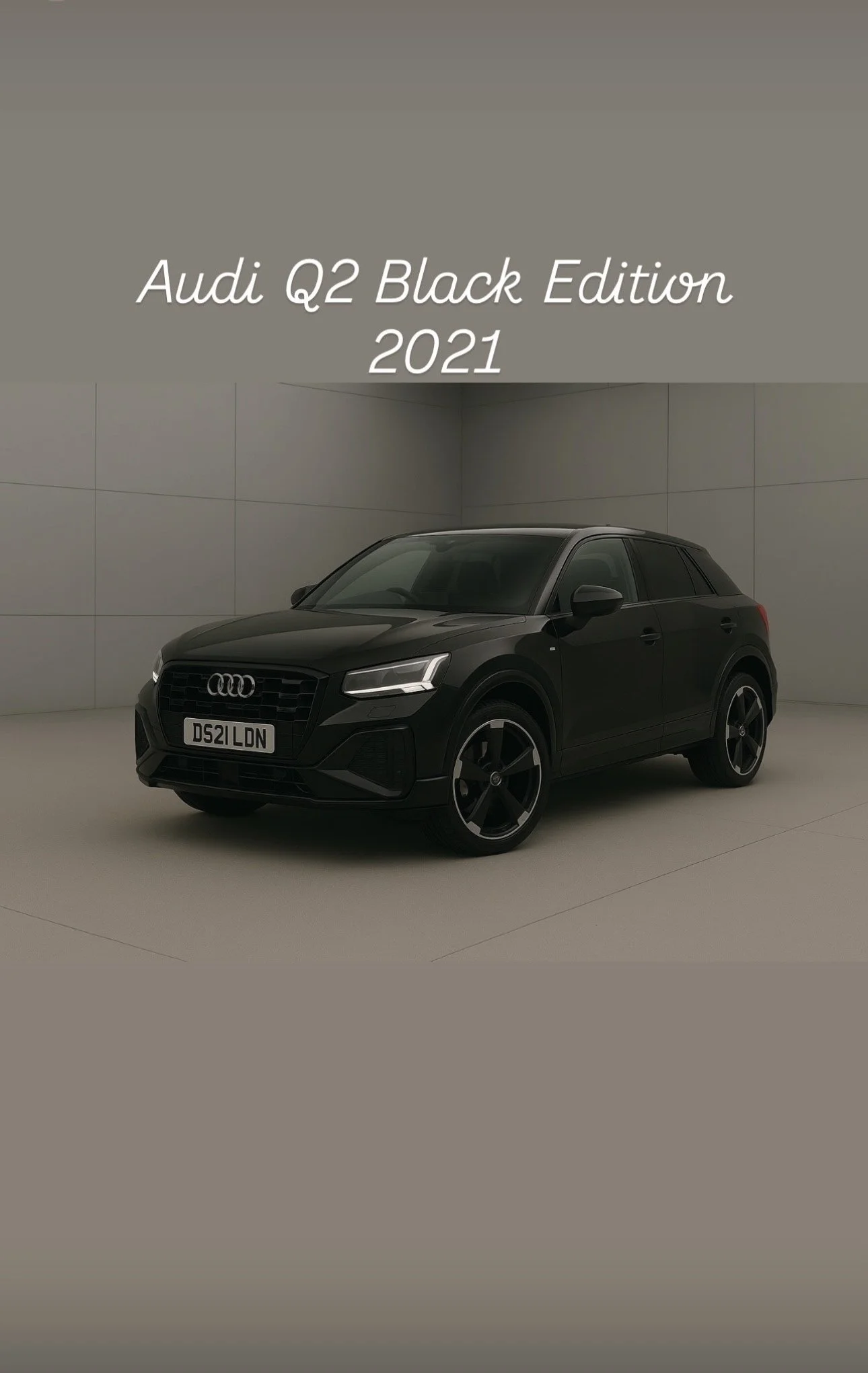 A black 2021 Audi Q2 Black Edition parked in a neutral-colored urban setting with textured walls.