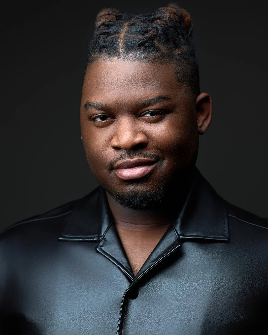 Professional headshot of an African America man wearing a black leather jacket