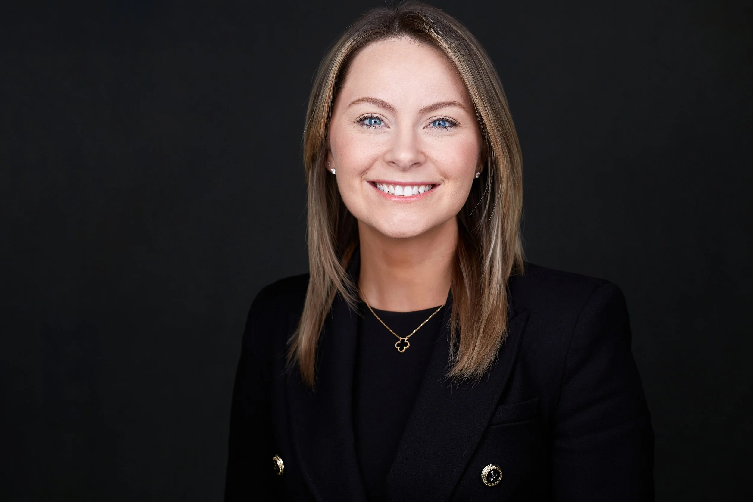 Smiling woman in professional attire with dark background