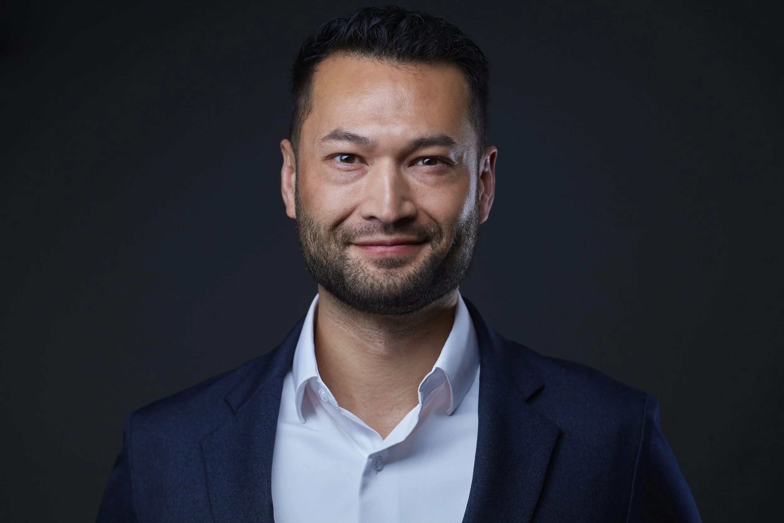 Smiling man in business attire against dark background