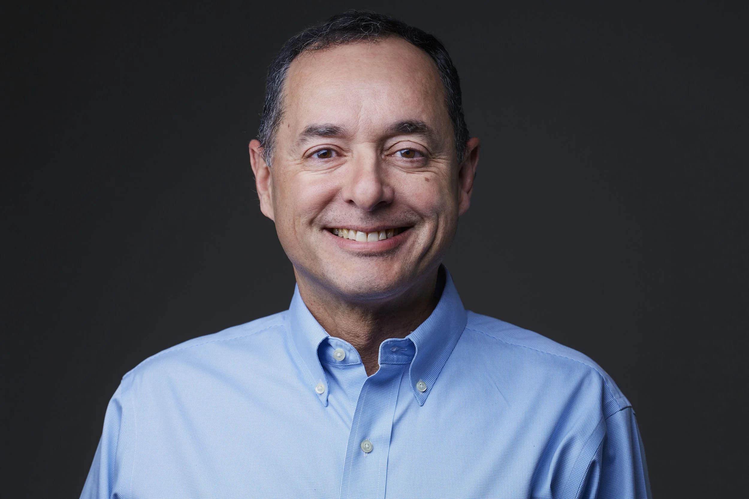 professional headshot of a business man wearing a lighter blue dress shirt.