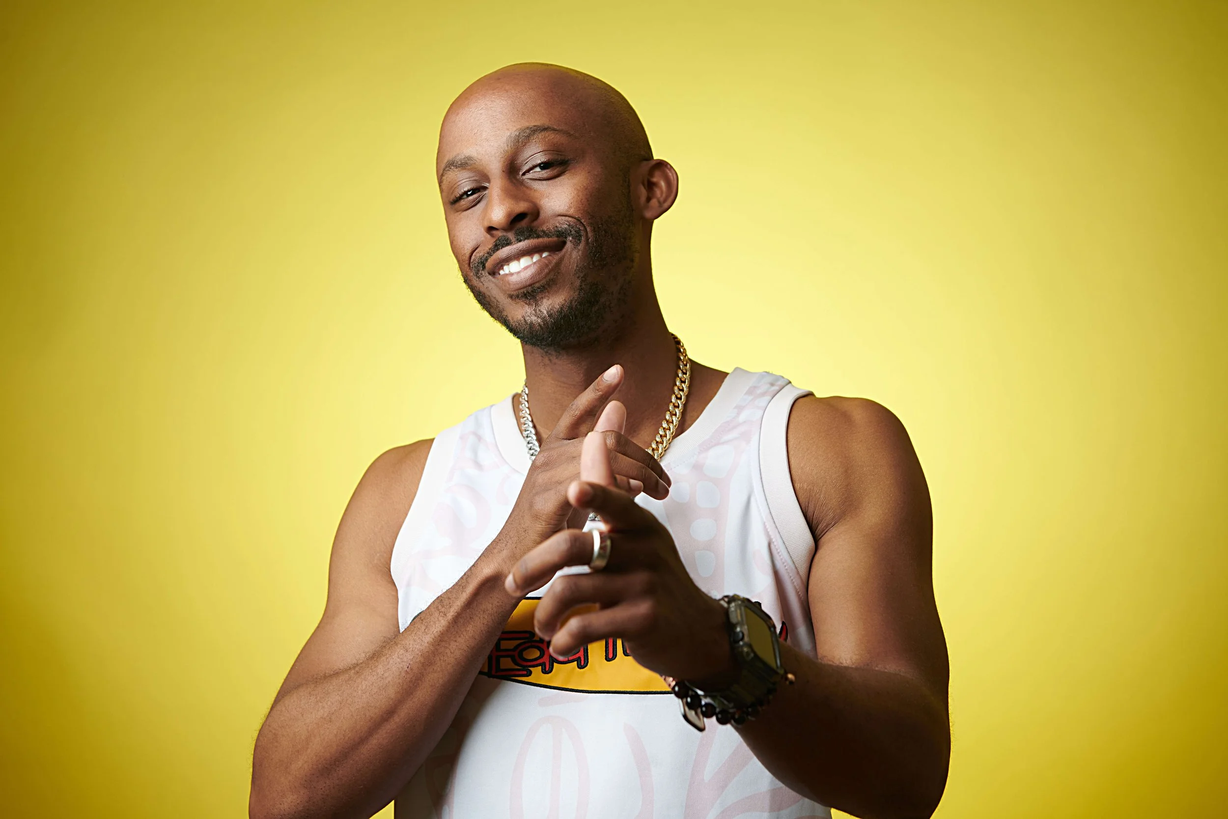professional creative headshot for a rockville, Maryland based actor wearing a wife-beater shirt against a yellow backdrop.