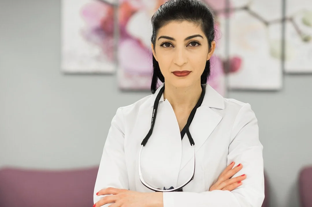 Headshot of a female dentist in her lobby wearing a white coat
