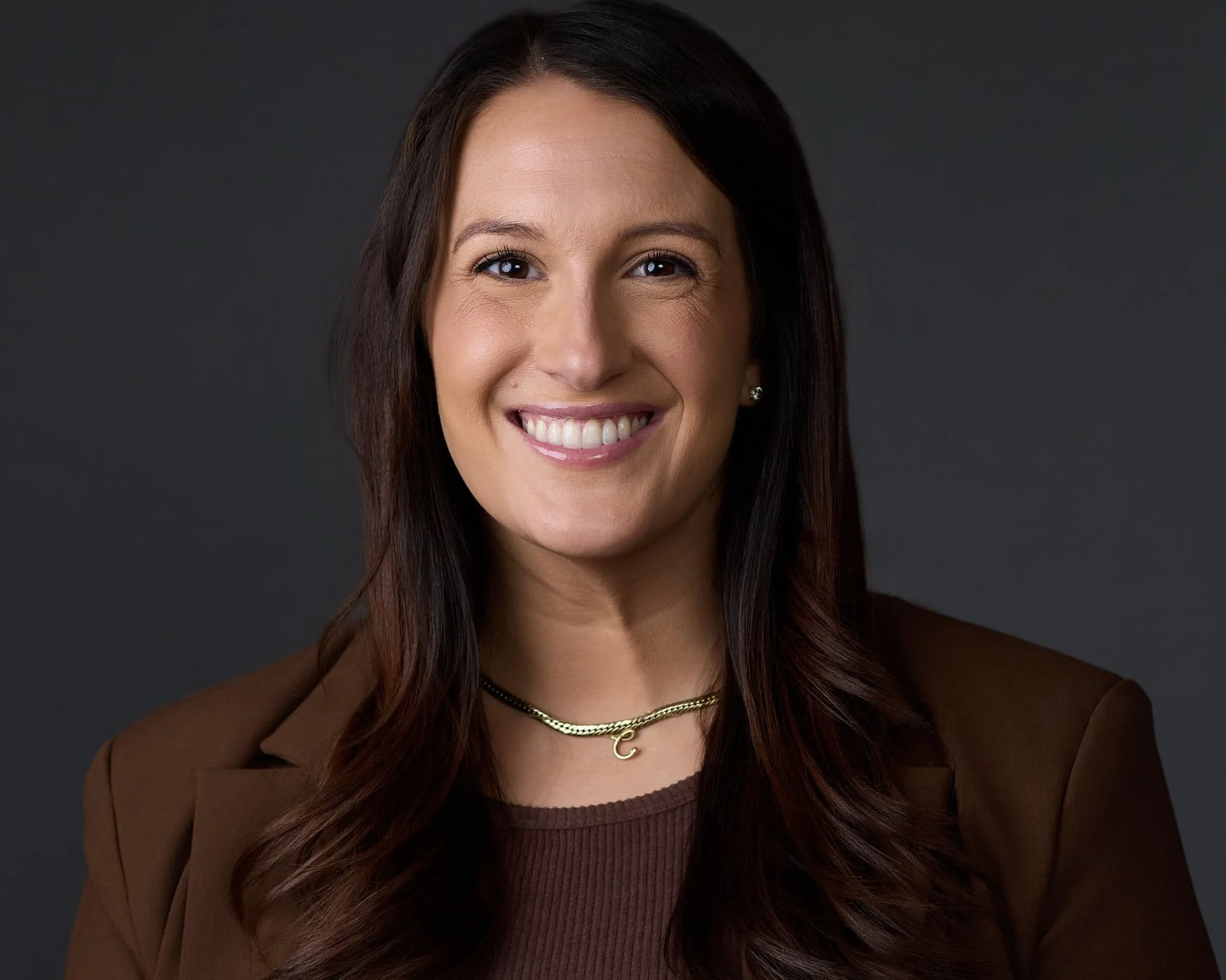 Headshot of a female doctor wearing a brown shirt and brown blazer