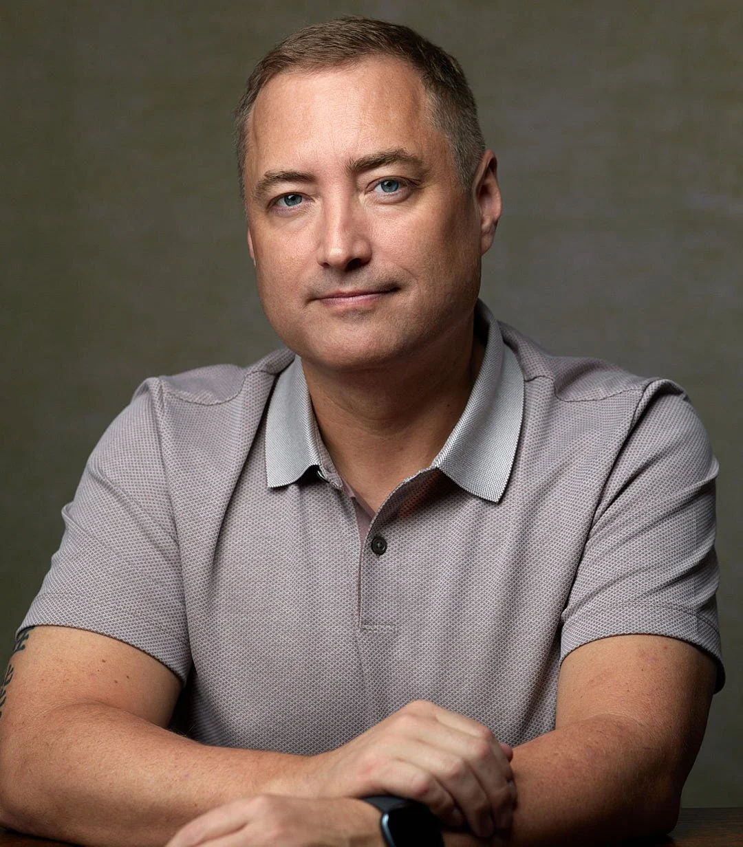 Headshot of a male actor against a green and beige backdrop