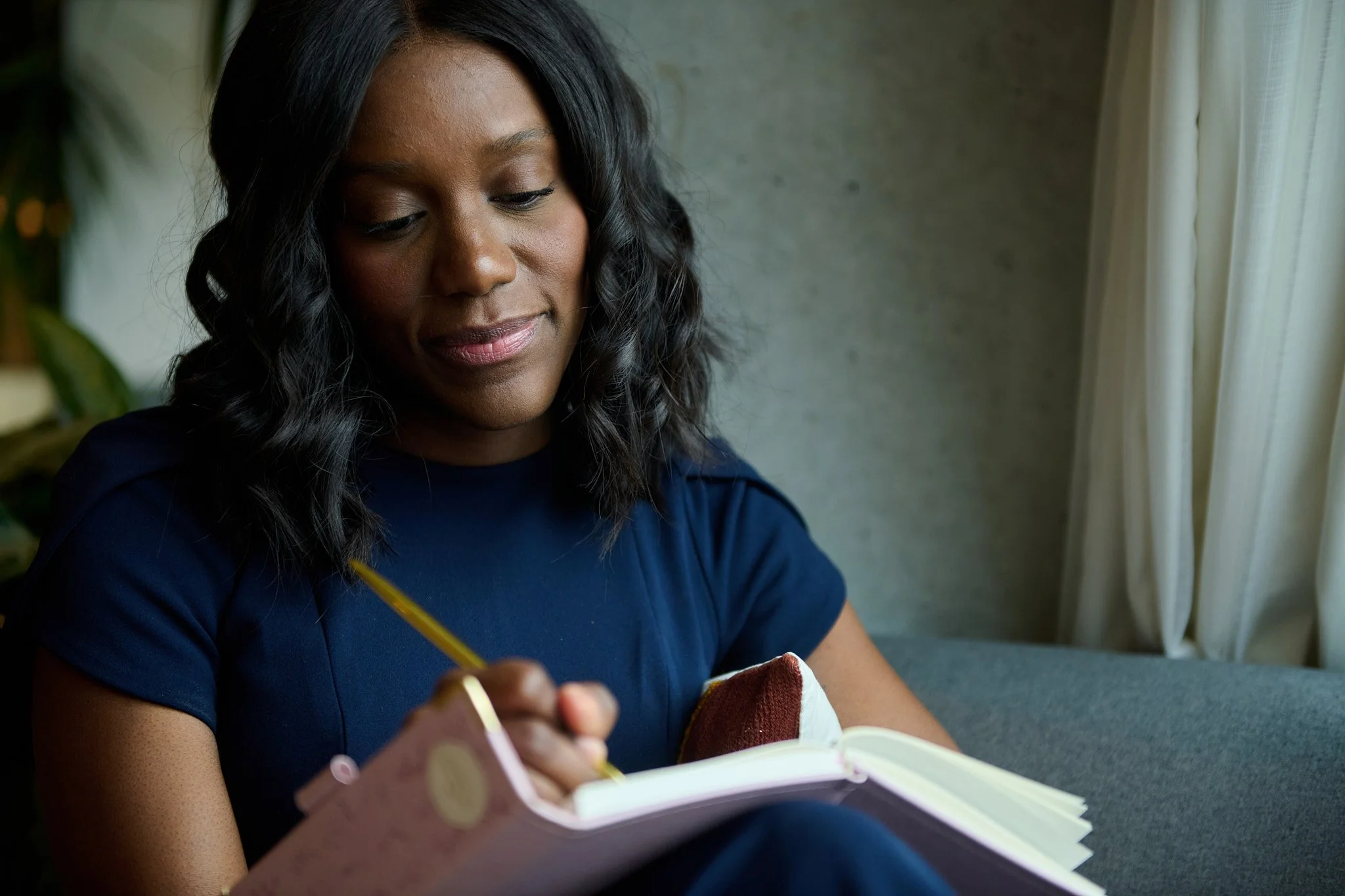 Personal Branding portrait of a woman sitting by a window brainstorming ideas into a journal