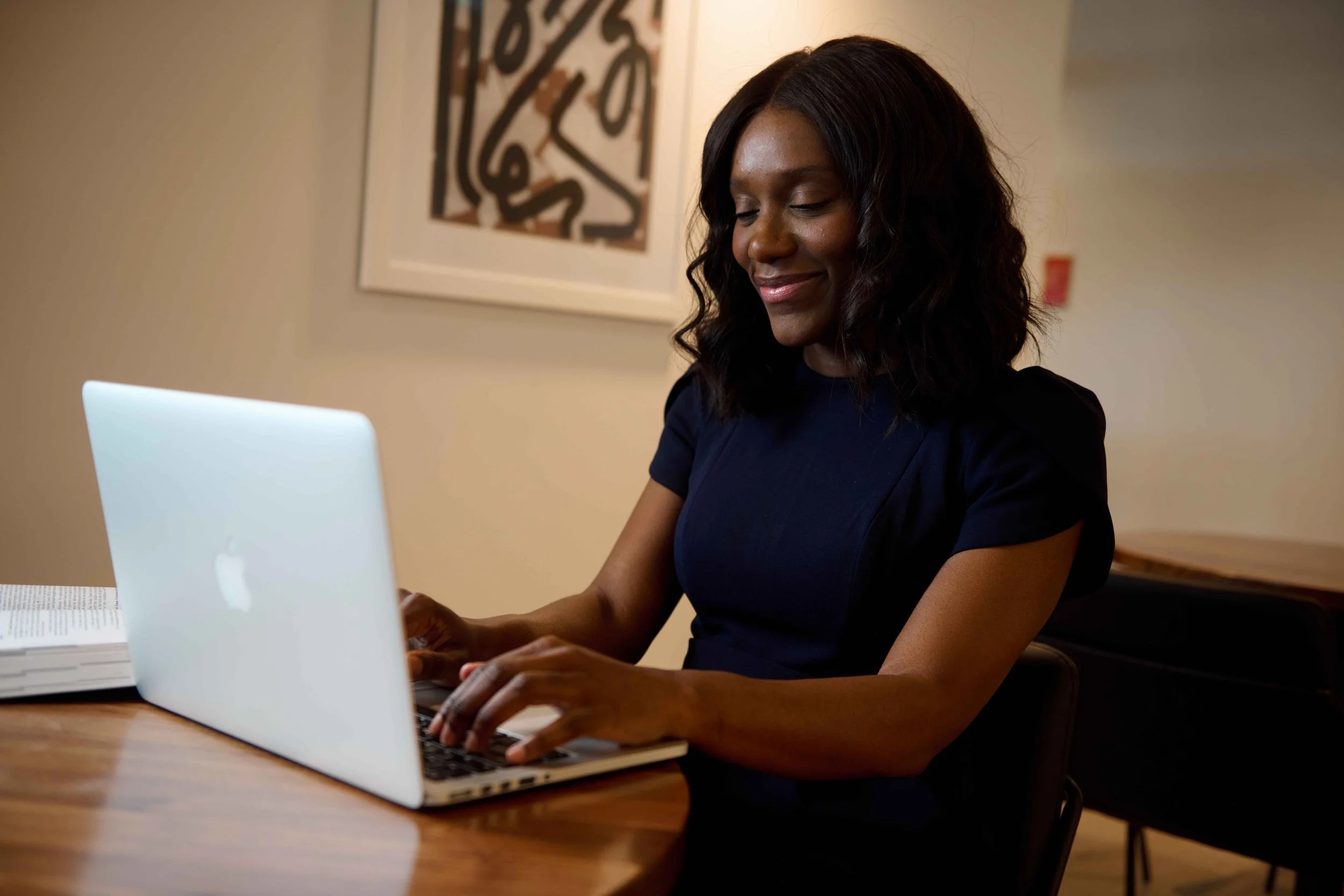 Personal branding portrait of a woman sitting at a table using her laptop