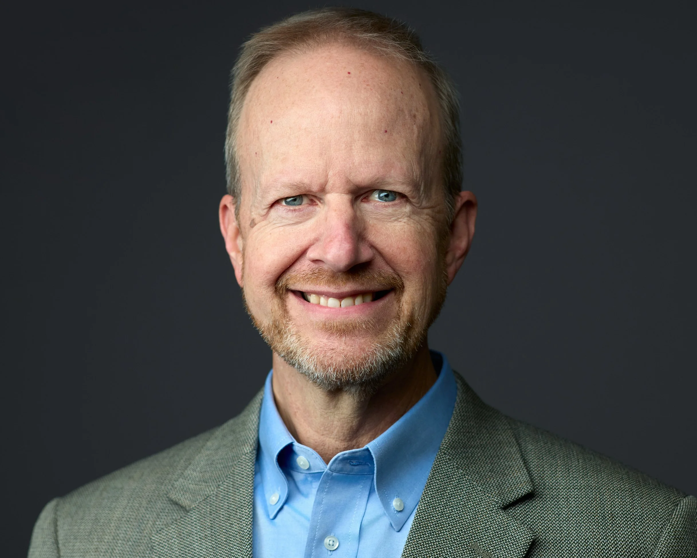 Professional Headshot of a man wearing a blue dress shirt and check blazer